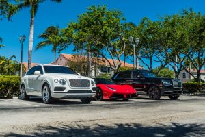 red ferrari black rolls royce cullinan side view three cars