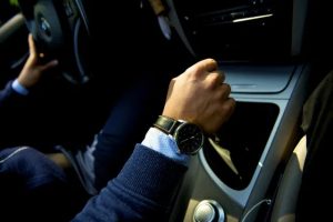 man wearing a navy blue suit driving a bmw with a nice watch